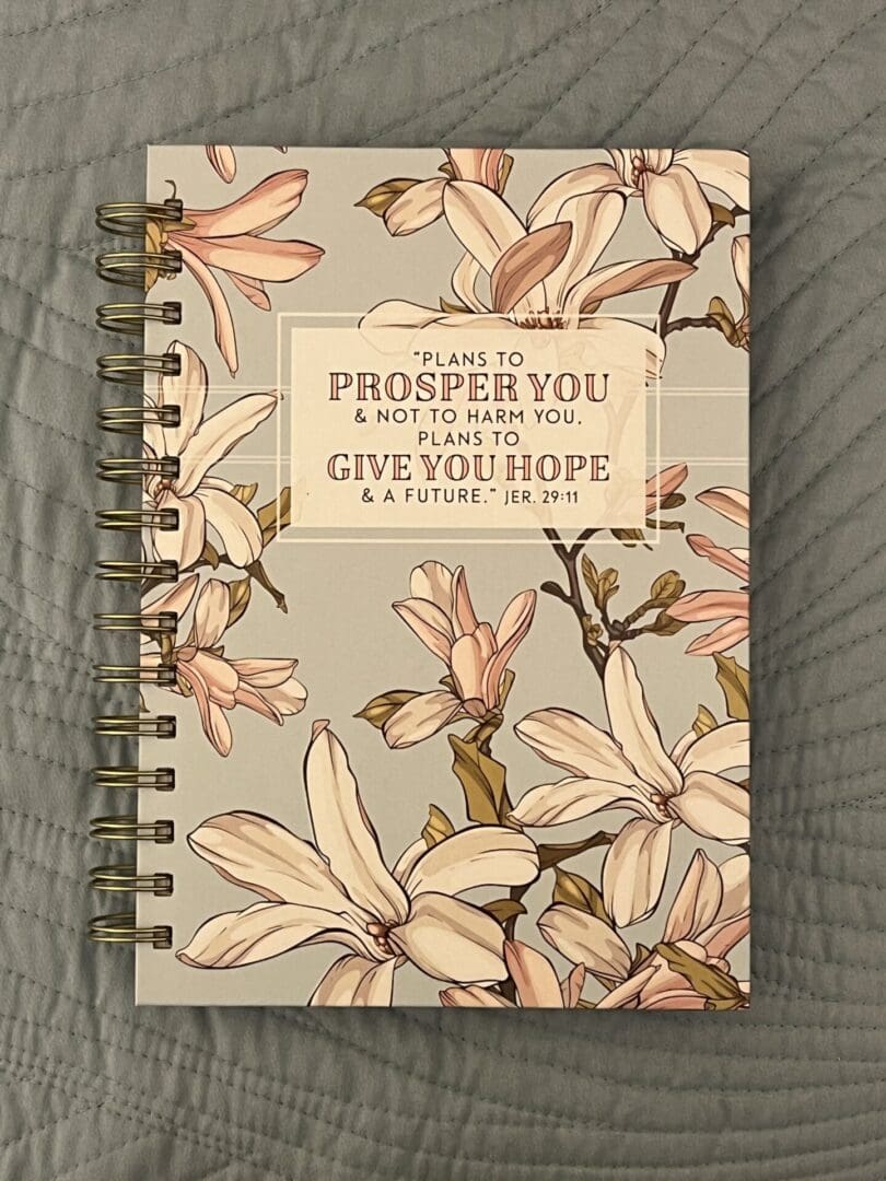 A notebook with a floral design and the words " to live is prosper you & not to mourn. It will give you hope ".